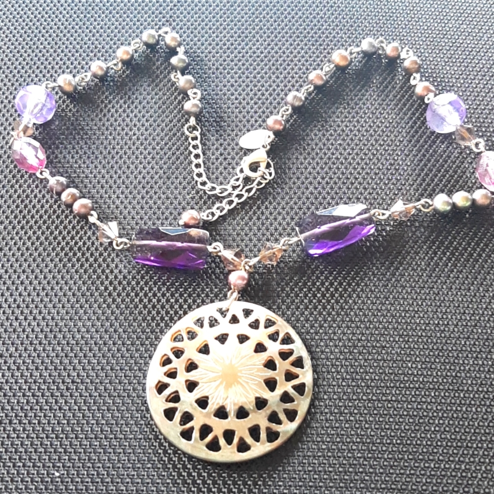 Gorgeous mother of pearl pendant with etching of a flower in the middle.
